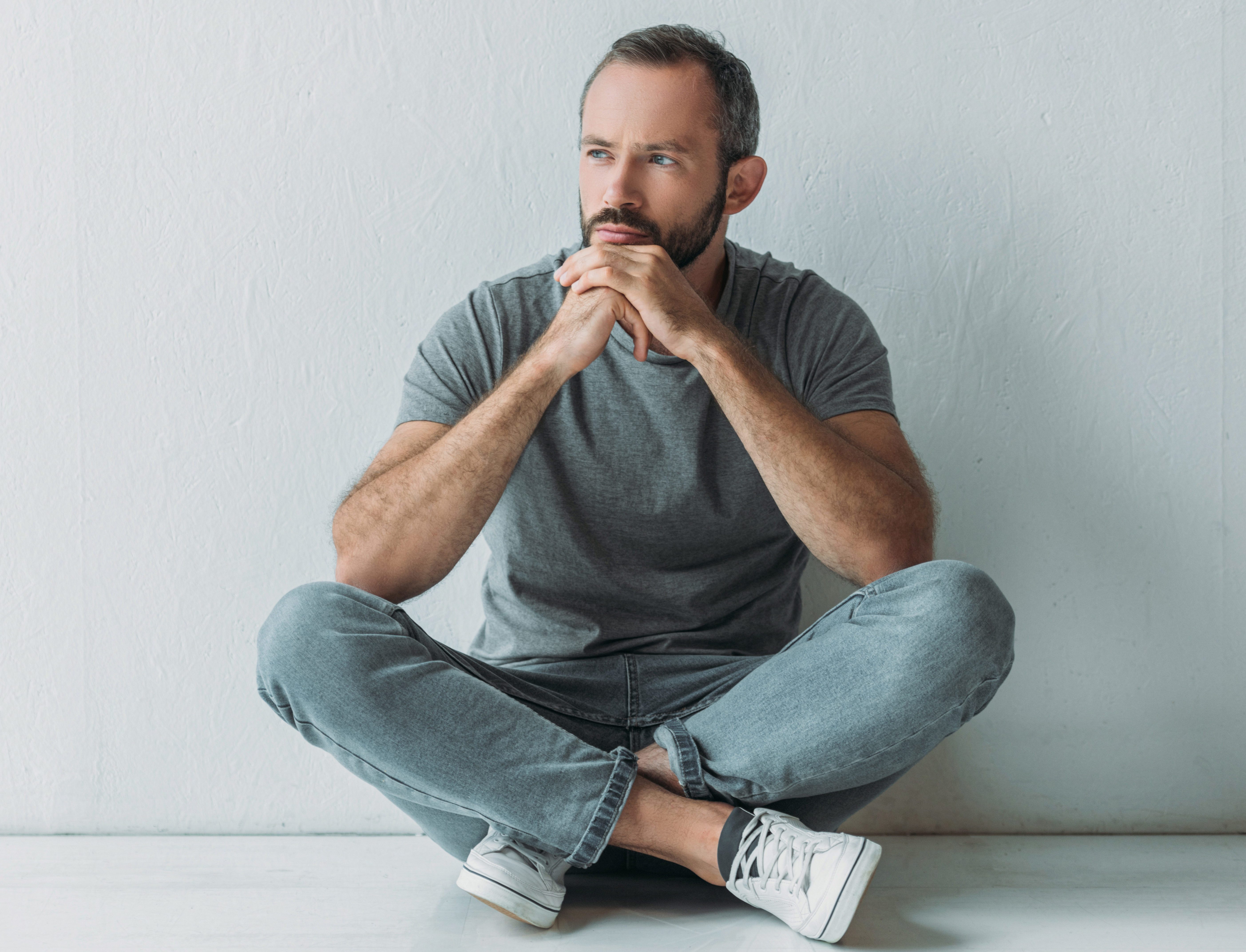 unhappy bearded man sitting in floor and looking away