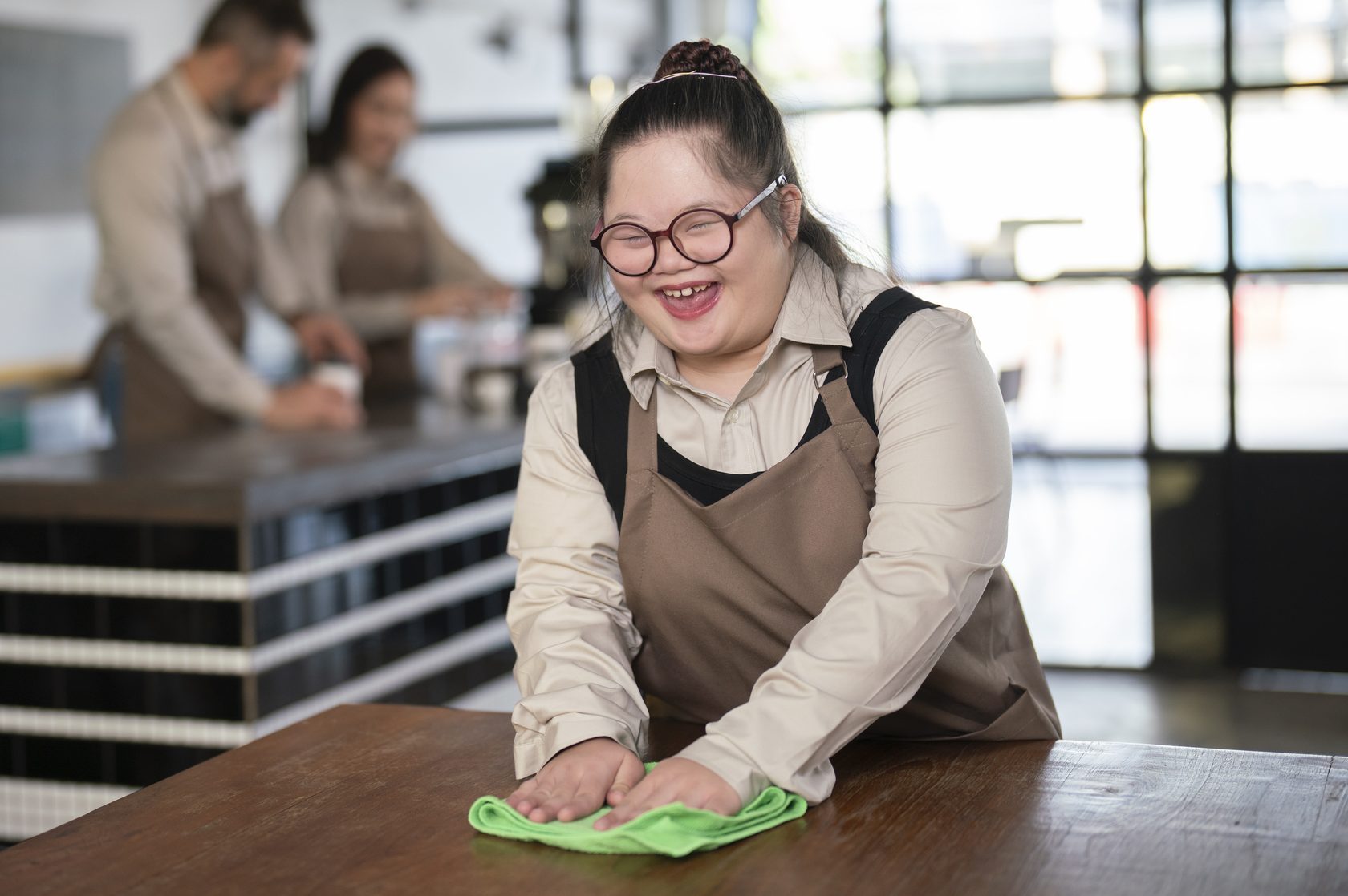 girl doing table slides with a green towel at a cafe 