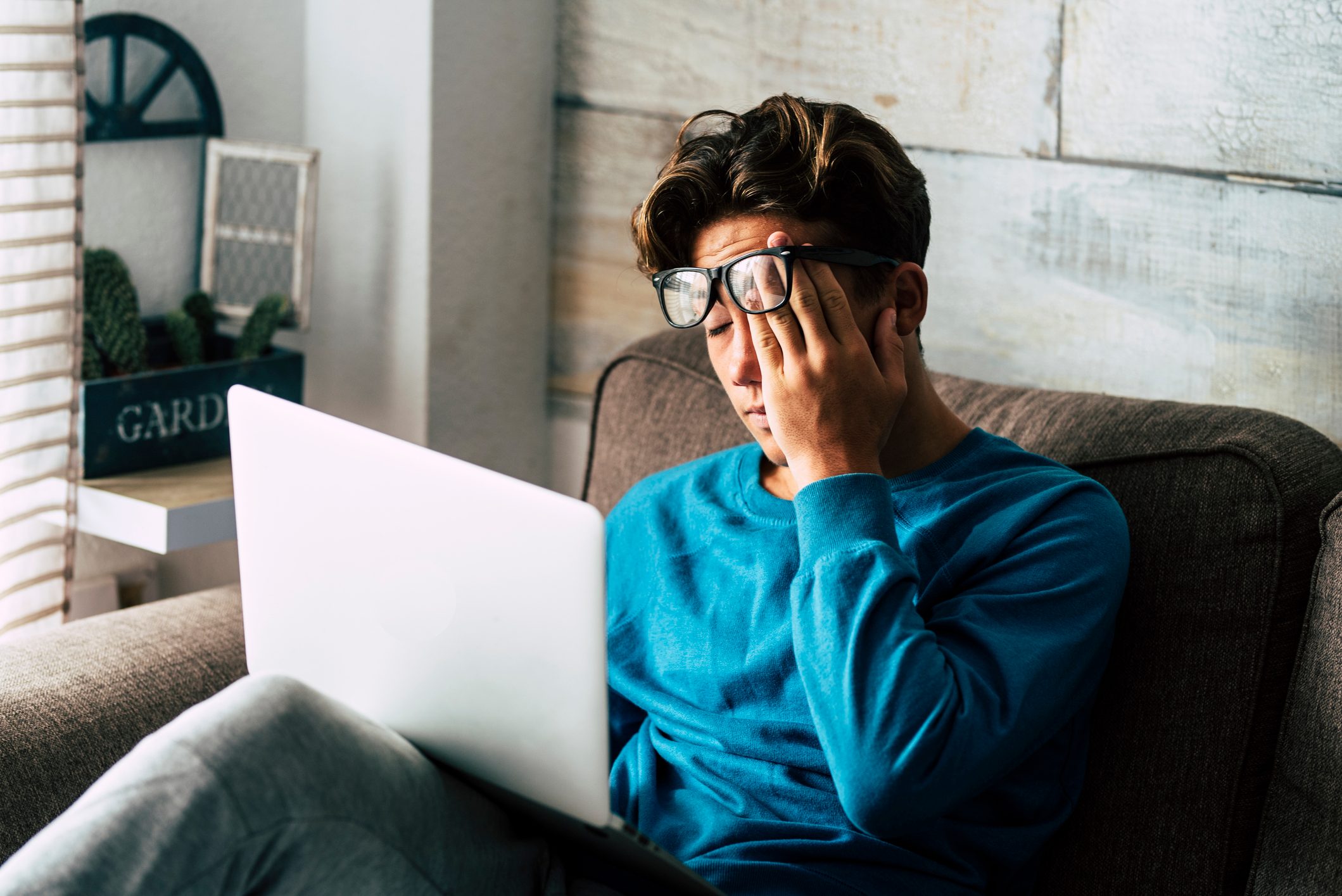 Stressed student at home studying with personal laptop computer - tired teenager for school work -internet. addiction for game or job search concept - indoor technology activity